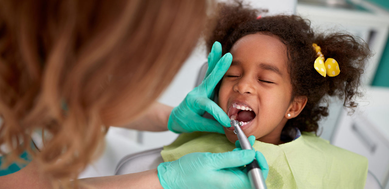 Female dentist patiently polish teeth to child  

